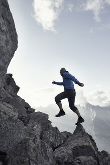 Älterer Mann springt auf Felsen, Wallis, Schweiz - CUF23893