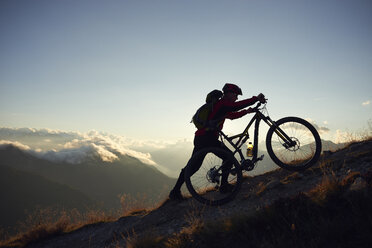 Mountainbiker schiebt sein Fahrrad bergauf, Wallis, Schweiz - CUF23897