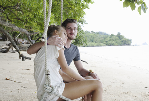 Junges Paar sitzt auf einer Strandschaukel, Kradan, Thailand, lizenzfreies Stockfoto