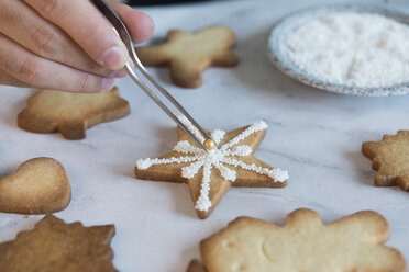 Männerhand beim Verzieren von Weihnachtsplätzchen, Nahaufnahme - SKCF00489