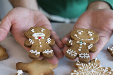 Man's hands holding two different Gingerbread Men, close-up - SKCF00490