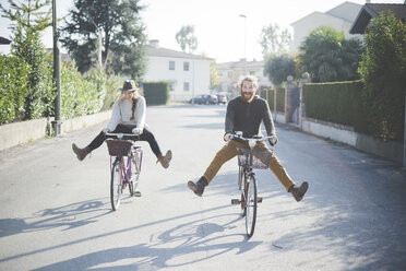 Young couple cycling with legs out - CUF24049