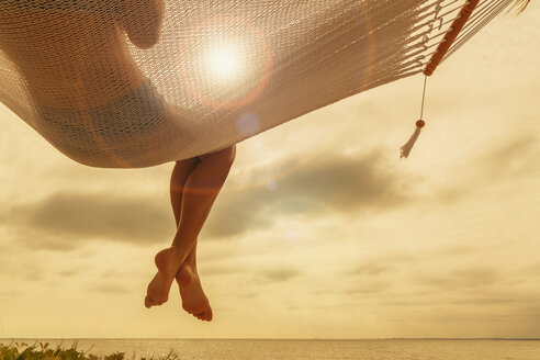 Rear view of young woman reclining on hammock at dusk on Miami Beach, Florida, USA - CUF24062