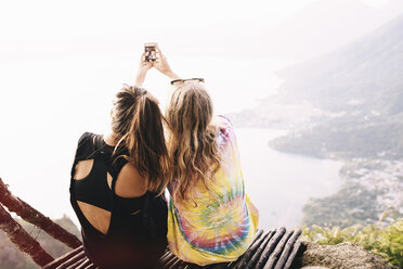 Rear view of two female friends taking smartphone selfie at Lake Atitlan, Guatemala - CUF24072