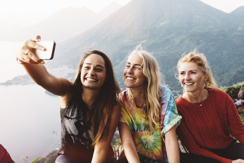 Drei Freundinnen machen ein Smartphone-Selfie am Atitlan-See, Guatemala, lizenzfreies Stockfoto