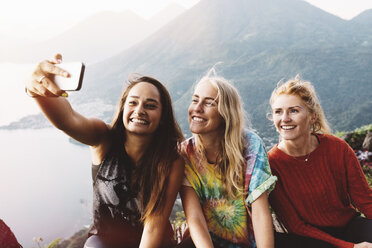 Three female friends taking smartphone selfie at Lake Atitlan, Guatemala - CUF24073