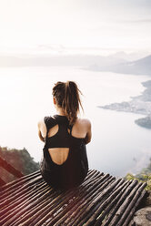 Rückansicht einer jungen Frau auf einem Balkon mit Blick auf den Atitlan-See, Guatemala - CUF24080