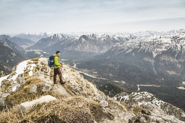 Young male hiker looking at view from Klammspitze mountain, Oberammergau, Bavaria, Germany - CUF24103