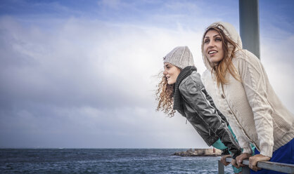 Zwei junge Freundinnen blicken vom Pier auf das Meer - CUF24160