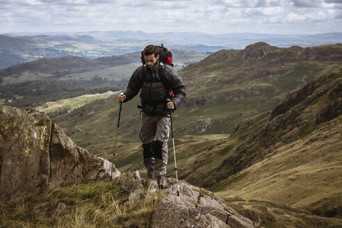Junger männlicher Wanderer beim Aufstieg auf einen Berg, Lake District, Cumbria, UK - CUF24171