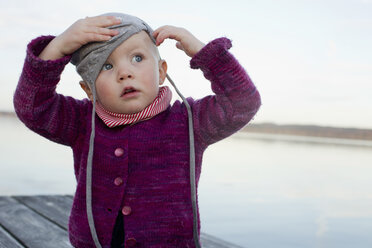 Baby-Mädchen auf See-Pier versucht, auf Hut setzen - CUF24173