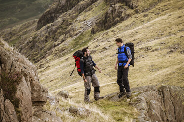 Zwei junge männliche Wanderfreunde lachen und unterhalten sich, The Lake District, Cumbria, UK - CUF24179