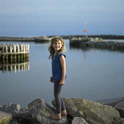 Mädchen steht auf einem Felsen am See - CUF24188