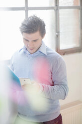 Young businessman reading texts on smartphone - CUF24255