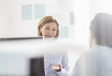 Businesswoman explaining to male colleague in office - CUF24258