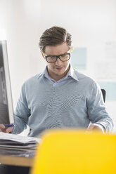 Young businessman doing paperwork at office desk - CUF24260