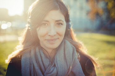 Portrait of mid adult woman listening to headphones in park - CUF24270