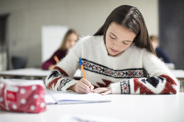 Teenager-Mädchen schreibt im Unterricht in ein Schulheft - ZEF15657