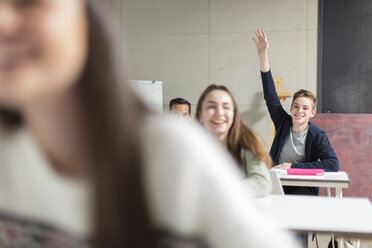 Lächelnder Teenager, der im Unterricht die Hand hebt - ZEF15661