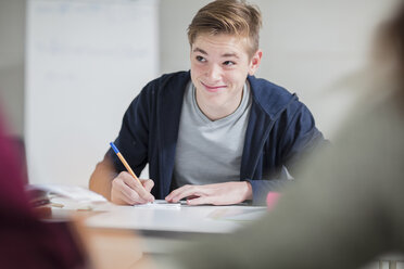 Lächelnder Teenager, der im Unterricht Notizen macht - ZEF15668