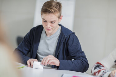 Teenage boy folding note in class - ZEF15669