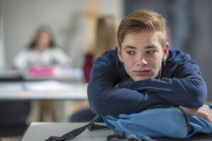 Serious teenage boy thinking in class - ZEF15673