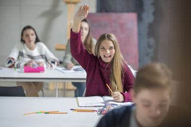 Happy teenage girl raising hand in class - ZEF15674