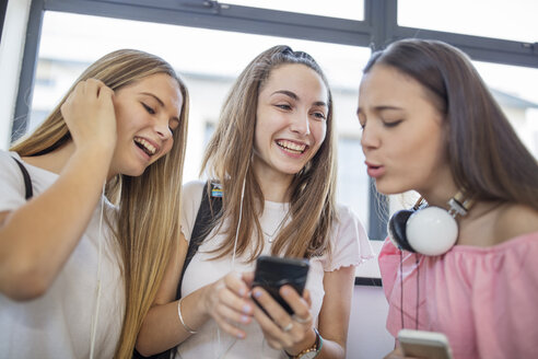 Glückliche Teenager-Mädchen benutzen Handys in der Schule - ZEF15710