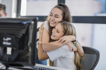 Happy teenage girls hugging in computer class - ZEF15720