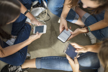 Teenager-Mädchen sitzen auf dem Boden und benutzen Handys - ZEF15732
