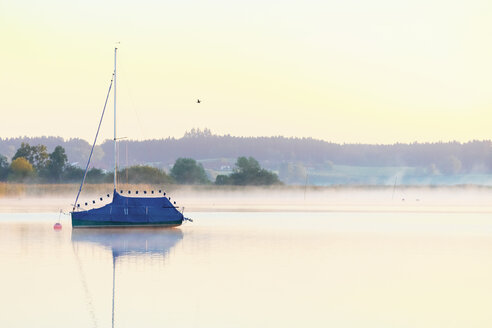 Deutschland, Bayern, Chiemsee, gedecktes Segelboot im Abendlicht - MMAF00379