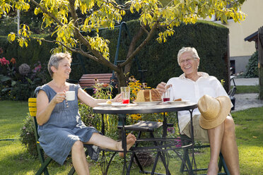 Älteres Paar, am Tisch im Garten sitzend, ein Getränk genießend - CUF24418