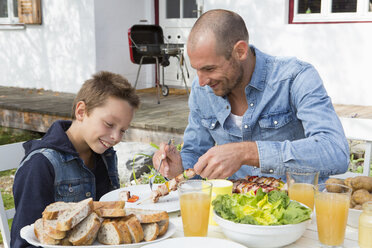 Father and son at garden barbecue table - CUF24426