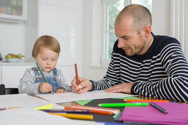 Mid adult man and toddler daughter drawing at kitchen table - CUF24428