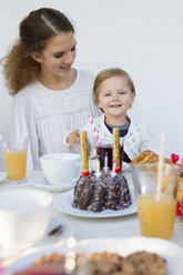 Teenage girl and toddler at patio table for birthday party - CUF24436