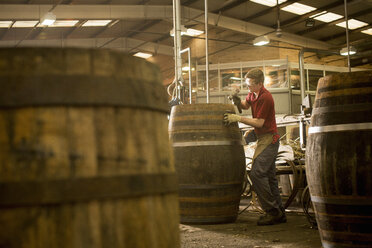 Junger Mann bei der Herstellung von Whiskyfässern in einer Küferei - CUF24513
