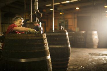 Älterer Mann bei der Herstellung von Whiskyfässern in einer Küferei - CUF24517