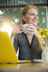 Young woman sitting in cafe, drinking coffee, using laptop - CUF24539