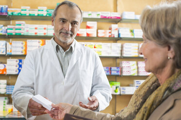 Pharmacist handing medicine to senior woman in pharmacy - CUF24604