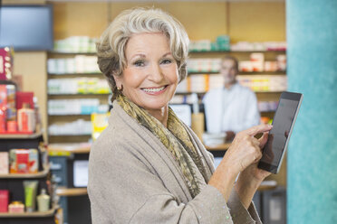 Porträt einer älteren Frau, die ein digitales Tablet benutzt, um in einer Apotheke Medikamente online zu bestellen - CUF24606