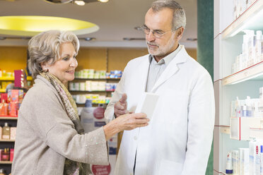 Pharmacist advising senior woman on medicine in pharmacy - CUF24613