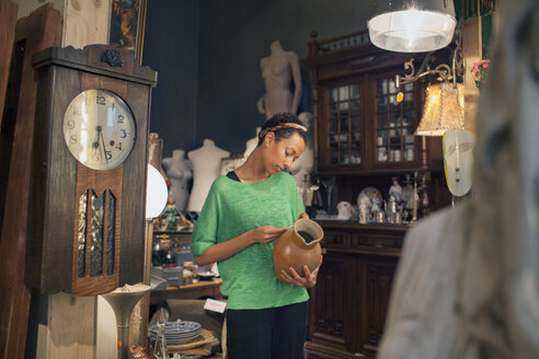 Junge Frau betrachtet Krug Preis Ticket in Vintage-Shop - CUF24634