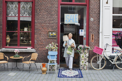 Ältere Kundin mit Lampe vor einem Vintage-Laden - CUF24638