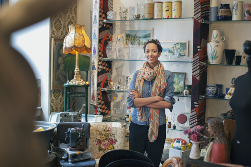 Portrait of young woman with arms folded in vintage shop - CUF24642