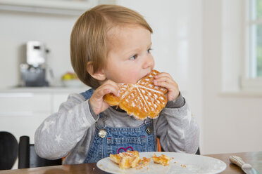 Nettes weibliches Kleinkind isst Kuchen am Küchentisch - CUF24684