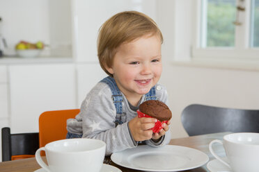 Niedliches weibliches Kleinkind hält Muffin am Küchentisch - CUF24685