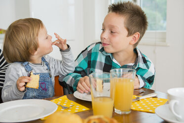 Cute female toddler licking fingers at kitchen table - CUF24686