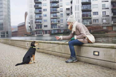 Mittlere erwachsene Frau und Hundetraining am Flussufer der Stadt - CUF24691