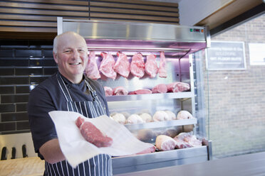 Portrait of butcher holding steak in butchers shop - CUF24694