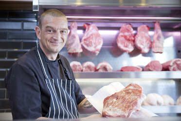 Porträt eines Metzgers mit frischem Fleisch in einer Metzgerei - CUF24696